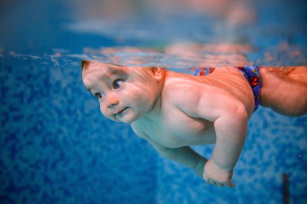 Un bébé de 7 mois nageant sous l'eau à la piscine