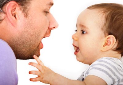 un bébé regarde la bouche de l'adulte qui lui parle