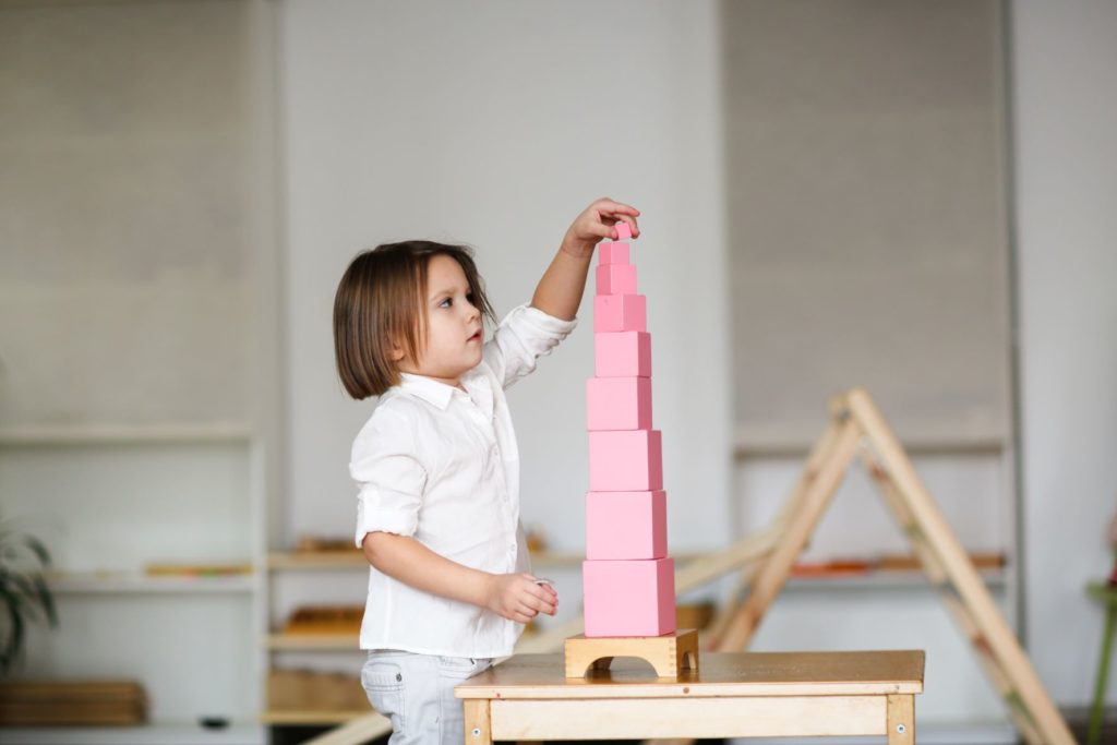 un enfant place le dernier cube de la tour rose